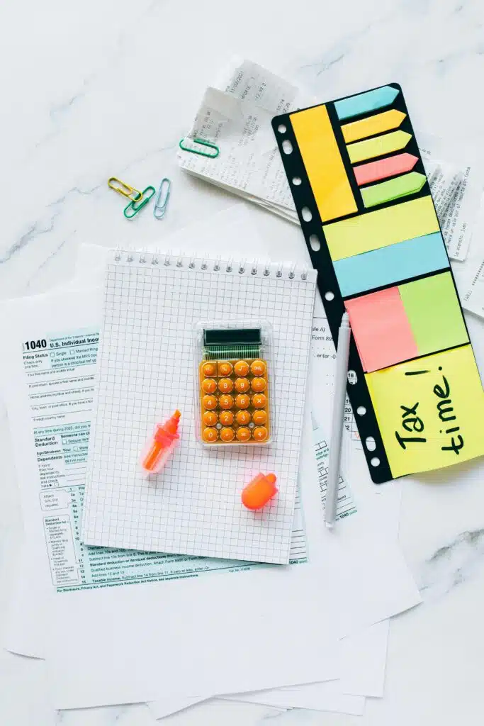 A vibrant gratuity preparation desk with documents, a calculator, and sticky notes for organization.