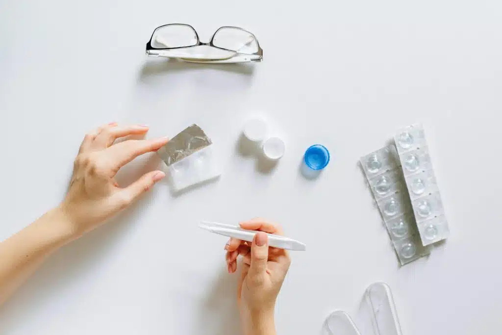 Flat lay setup of contact lenses with eyeglasses for eye care on a white background.