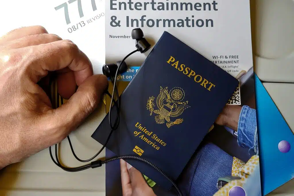 Close-up of US passport with inflight magazine and headphones on an airplane seat, ready for travel.