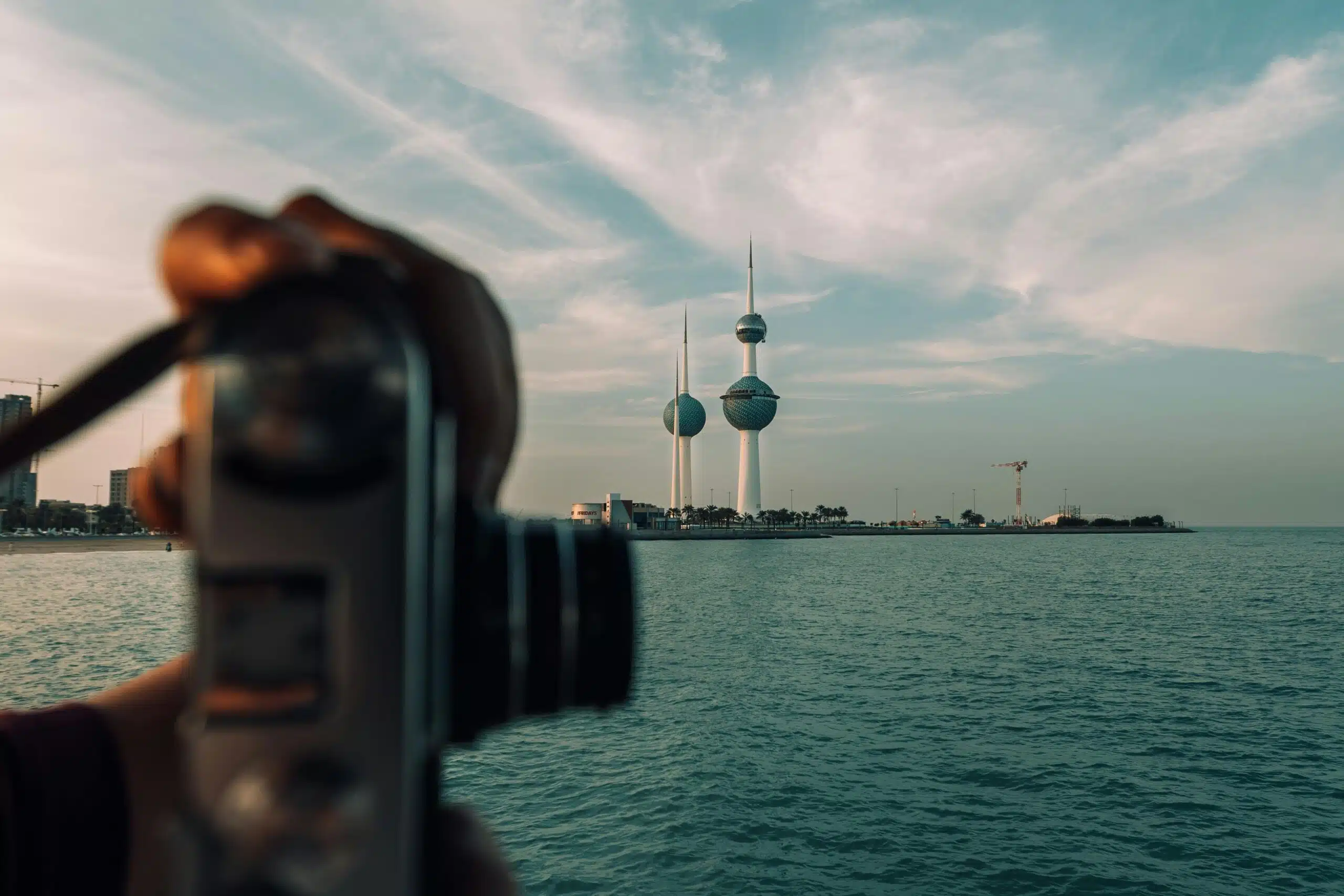 A vintage camera capturing the iconic Kuwait Towers against a serene seascape.