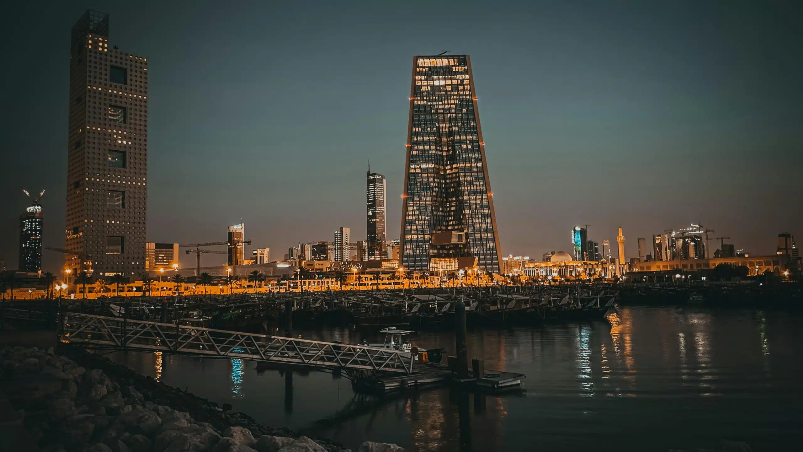 Stunning twilight cityscape featuring modern skyscrapers reflecting in water under a dusky sky.